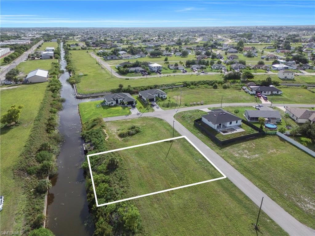 Expansive canal-front lot featuring a grassed area, mature foliage, and direct water access