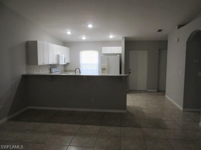 Kitchen featuring white cabinetry, light countertops, and a breakfast bar
