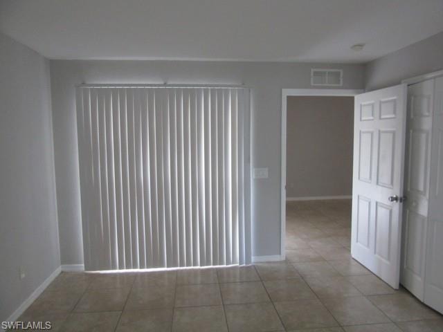 Room featuring light gray walls, tile flooring, and vertical blinds on the sliding glass door