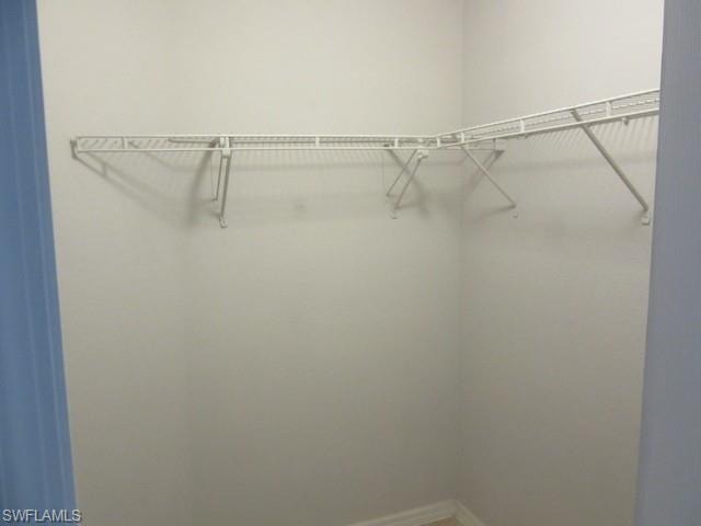 Walk-in closet featuring white wire shelving and hanging rods