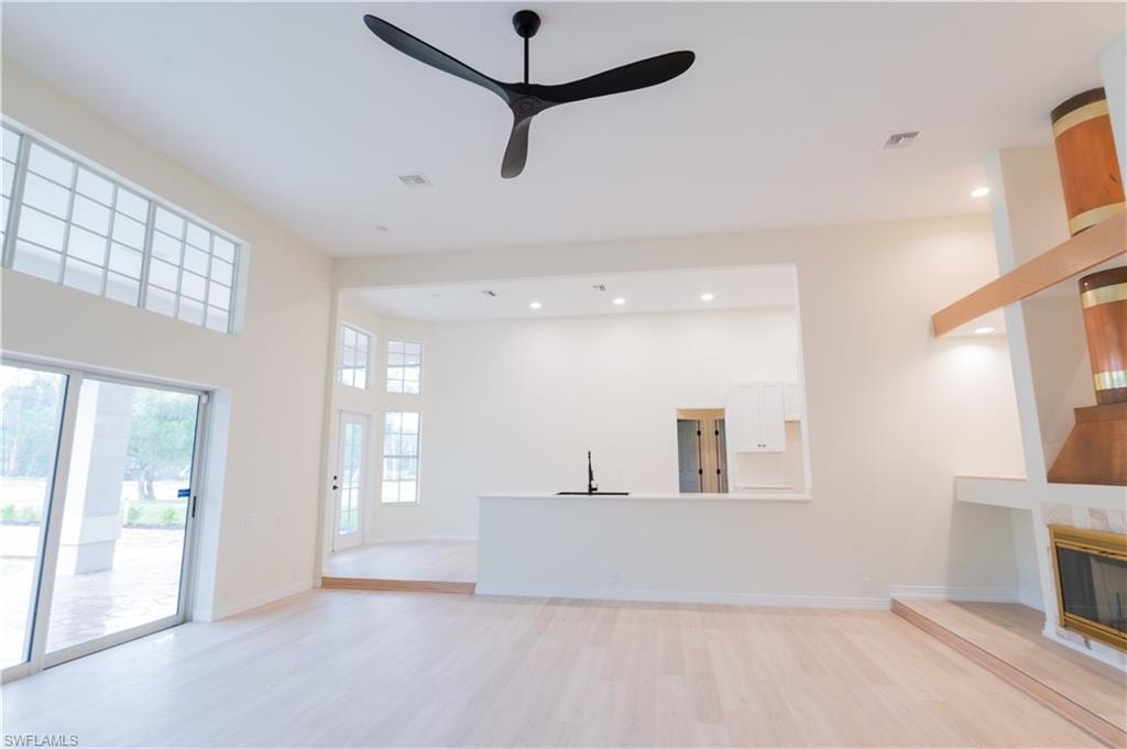 Spacious open-concept living area featuring light wood-finish flooring, a contemporary ceiling fan, and recessed lighting