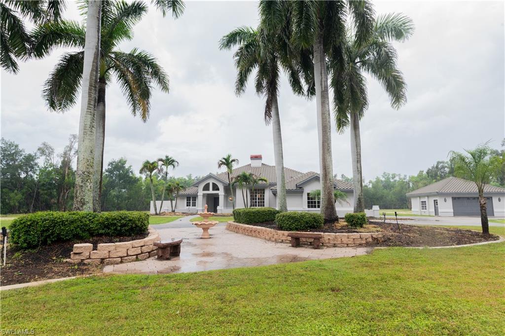 Circular driveway featuring a central fountain and stone-faced planters