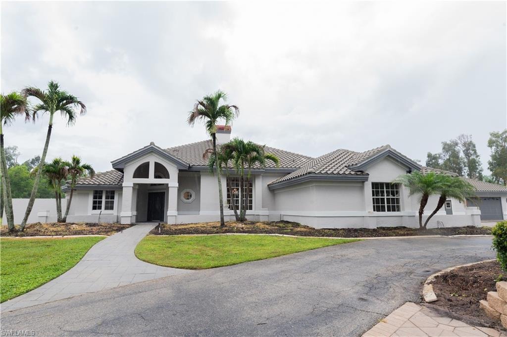 Single-story residence featuring a tile roof, arched entryway, and multiple windows