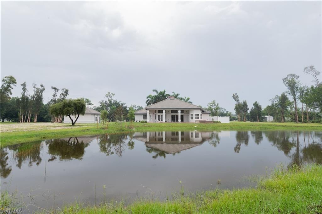 Expansive property featuring a large body of water, lush green banks, and mature trees