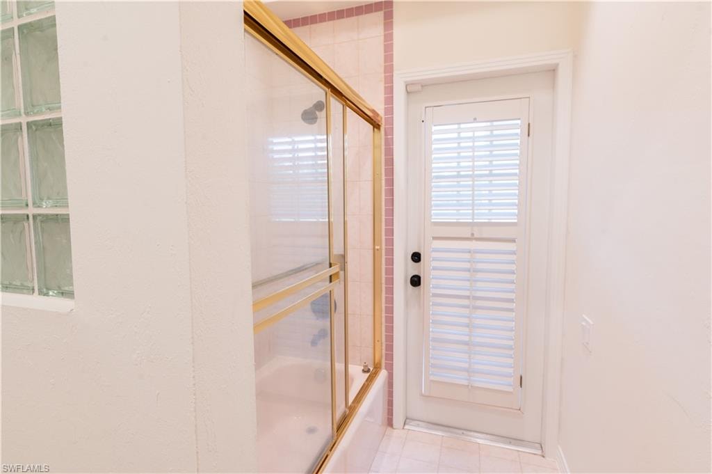 Walk-in shower featuring large format veined wall tiles, a mosaic tile floor, and matte black fixtures including a shower head and control