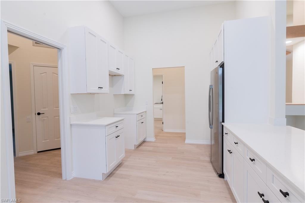 Kitchen featuring white shaker-style cabinetry, light wood-finish flooring, and light countertops