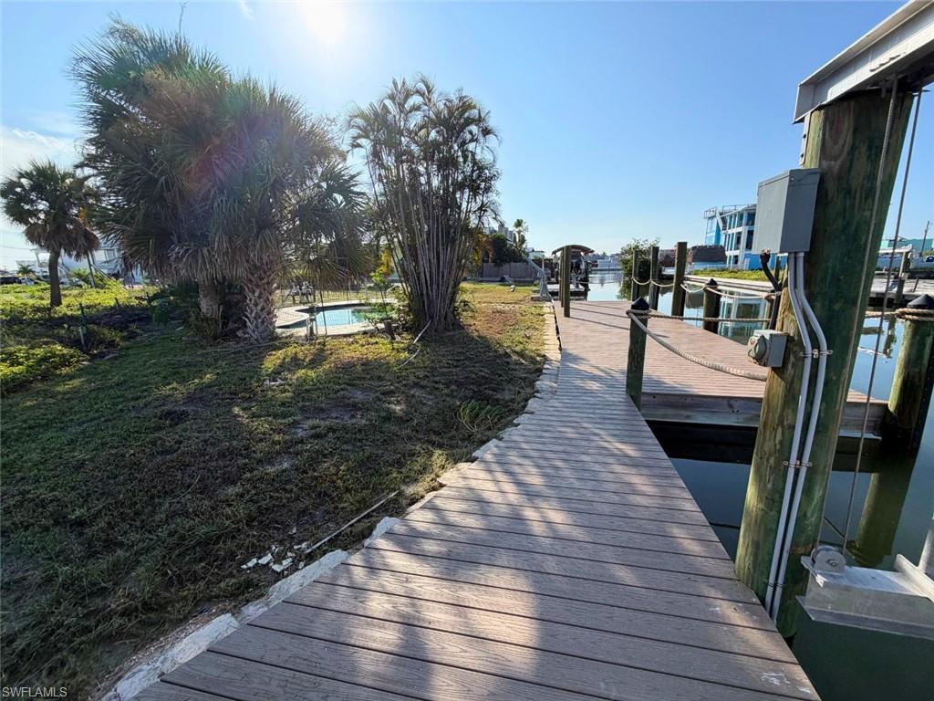 Waterfront property featuring a composite wood dock, multiple boat slips, and a swimming pool - Virtually Edited Image