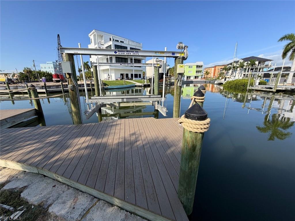 Waterfront property featuring a private boat dock with a lift system, composite decking, and direct canal access - Virtually Edited Image