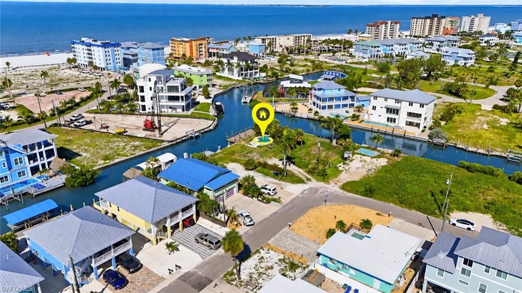 Canal-front property featuring direct water access, a sandy beach shoreline, and a vibrant coastal community backdrop - Virtually Edited Image
