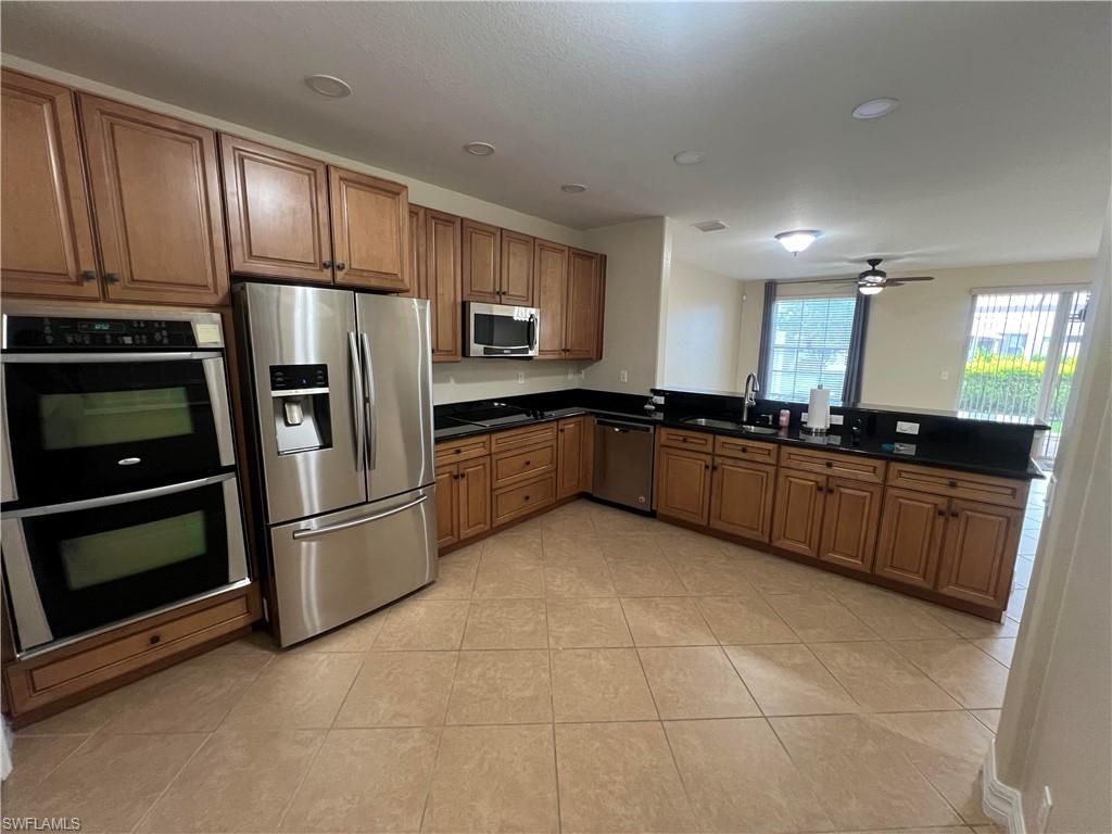 Kitchen with sink, kitchen peninsula, light tile floors, and stainless steel appliances