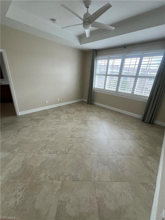 Bedroom featuring a raised ceiling, ceiling fan, and light tile floors