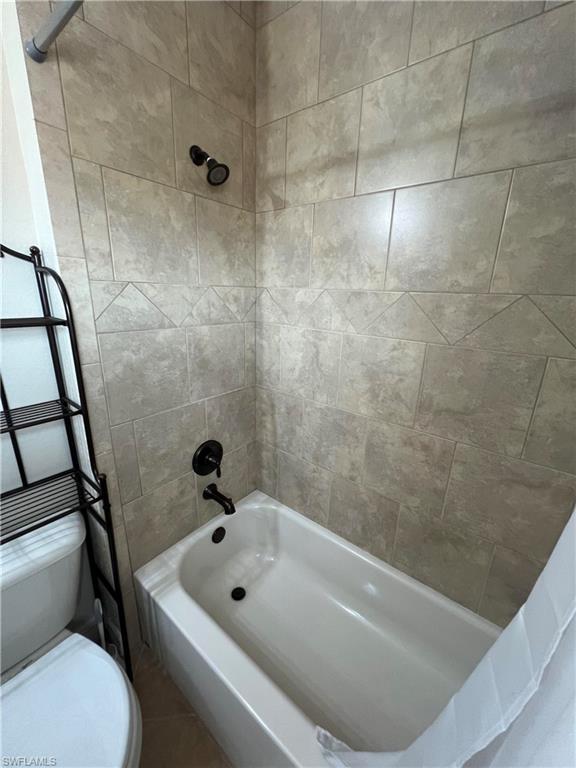 Bathroom with tiled shower / bath and toilet
