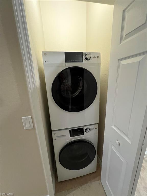 Washroom with stacked washer / dryer and light tile flooring