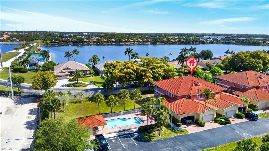 Waterfront property featuring a red tile roof, an attached garage, mature palm trees, and a community pool