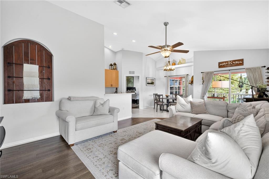 Spacious living area featuring high vaulted ceilings, modern ceiling fan, wood-finish flooring, and a decorative arched wall niche