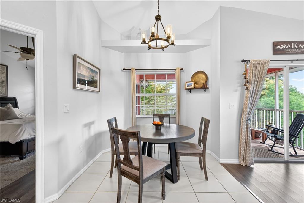 Dining area featuring vaulted ceilings, a contemporary chandelier, and a large window