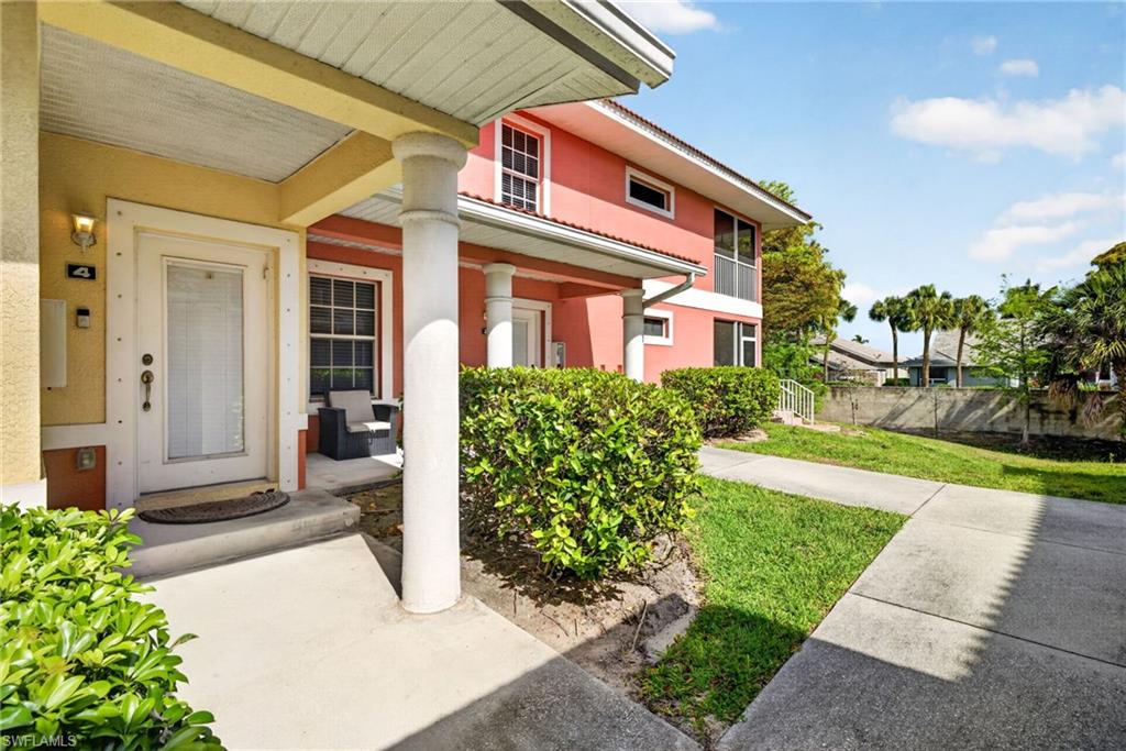 Front entry with a columned porch, surrounded by established shrubbery and concrete walkways