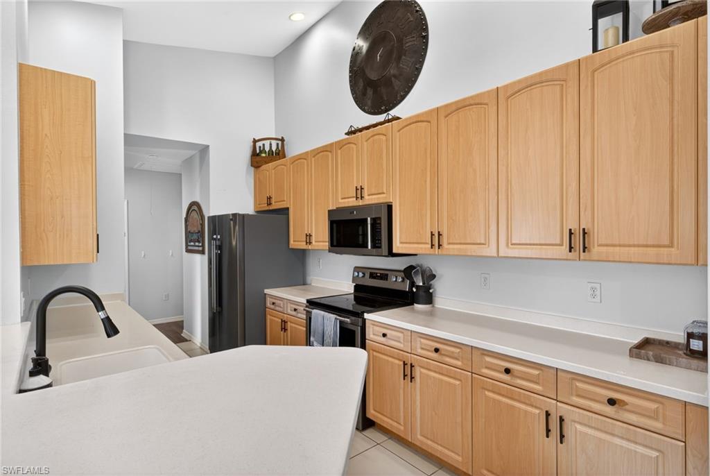 Kitchen featuring light wood cabinetry, white countertops, built-in microwave, and stainless steel appliances