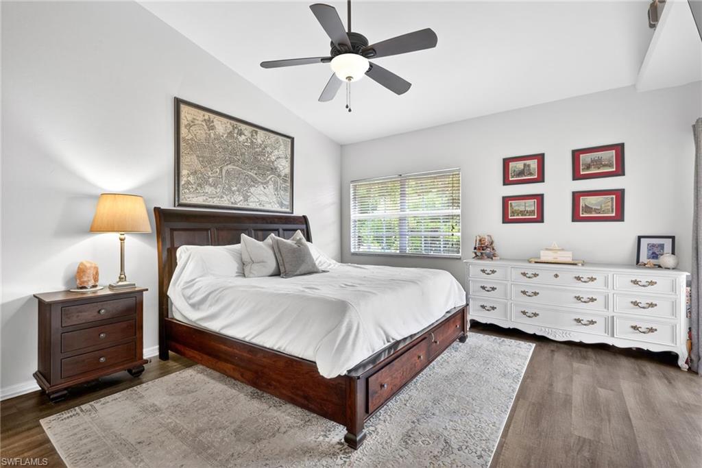 Spacious bedroom featuring wood-finish flooring, a ceiling fan with integrated lighting, and a window with blinds