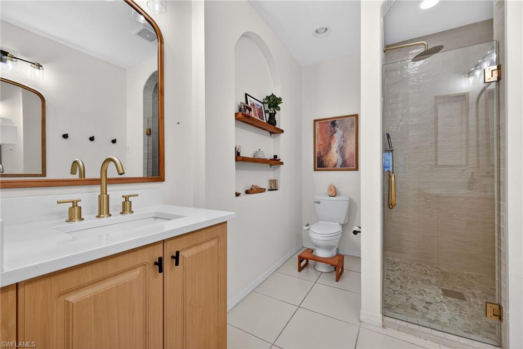 Bathroom vanity featuring a rectangular undermount sink with brass-finish faucet, quartz countertop, and light wood cabinetry
