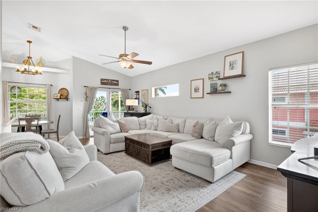 Spacious living area featuring vaulted ceilings, wood-finish flooring, and a ceiling fan