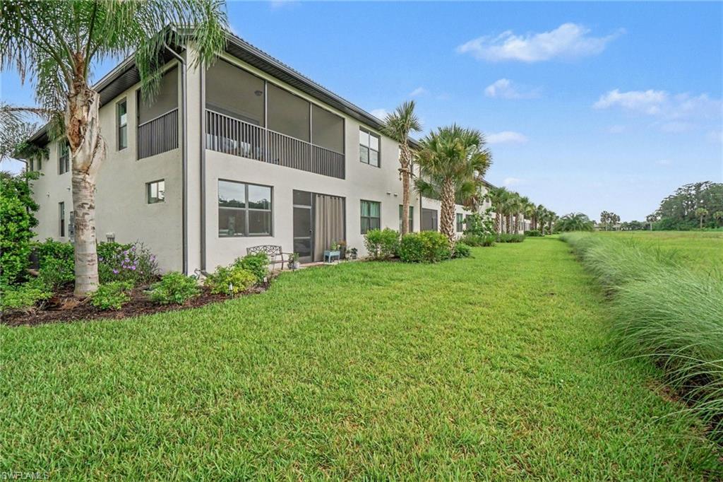 Rear exterior featuring a screened-in upper balcony, ground-level screened patio, and mature palm trees