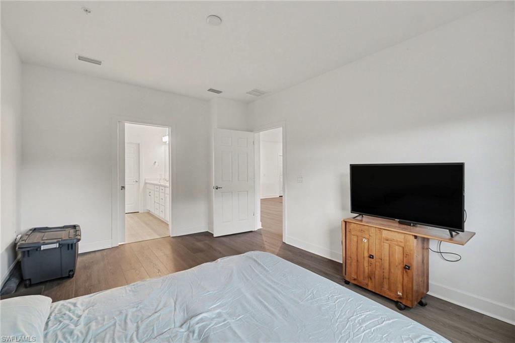 Interior room featuring dark wood-finish flooring, white walls, and bright overhead lighting