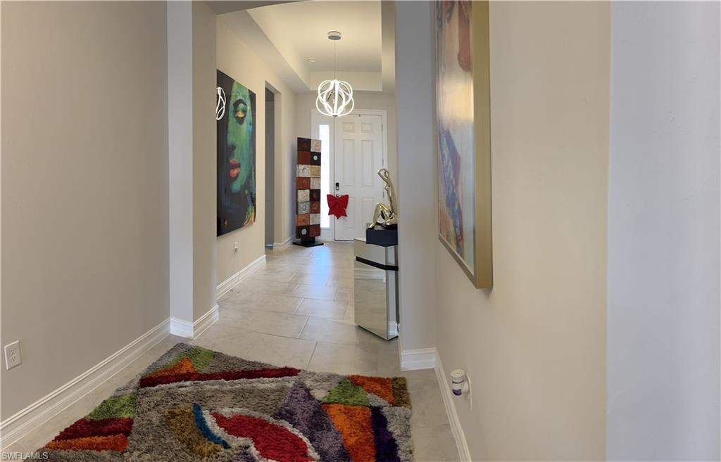 Hallway featuring light-toned tile flooring, recessed lighting, and a contemporary pendant light fixture