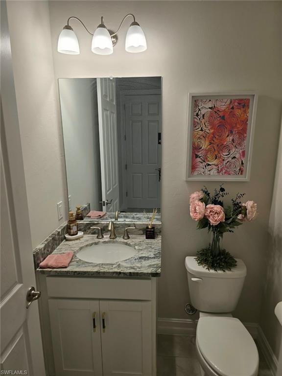 White vanity with gold-finish hardware, undermount sink, and a stone countertop