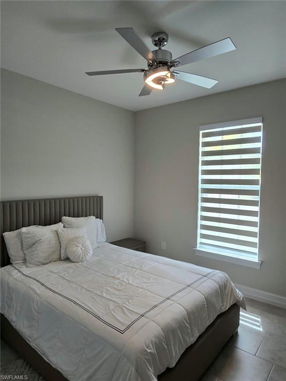 Modern ceiling fan with integrated lighting, window with horizontal blinds, and tile flooring