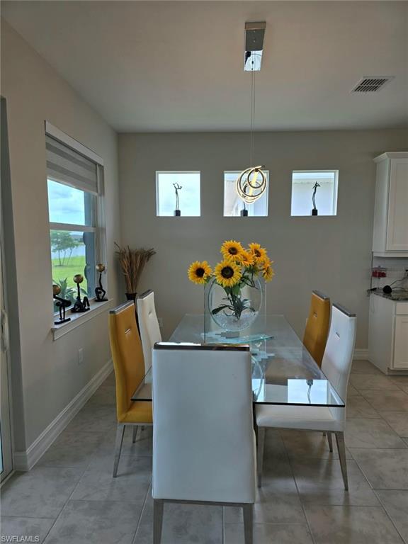 Dining space featuring tiled flooring, a glass-top table, and a modern pendant light fixture
