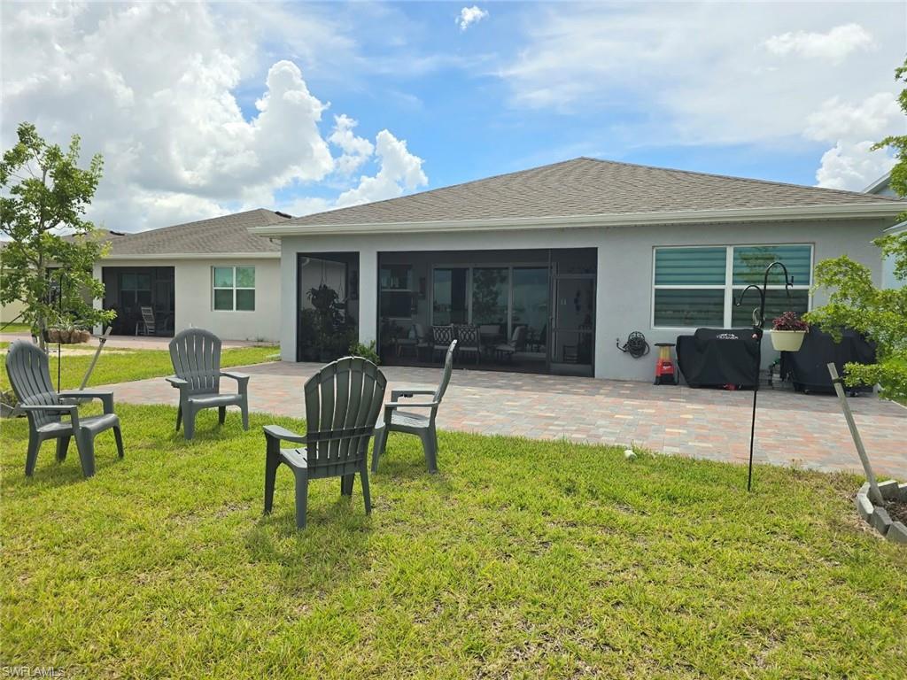 Expansive backyard featuring a manicured lawn, paver patio, and screened lanai with sliding glass doors