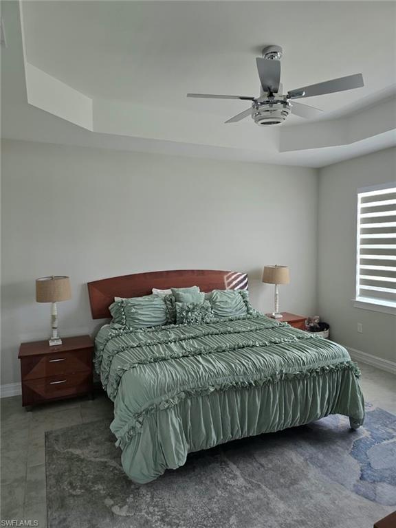 Tray ceiling with a ceiling fan, tile flooring, and window with horizontal blinds