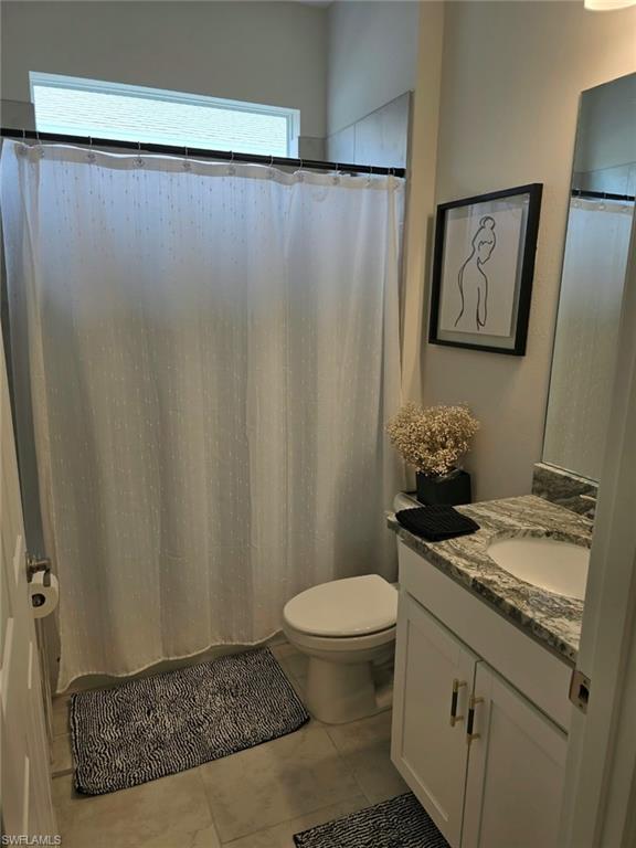 Bathroom featuring a vanity with a stone countertop, an undermount sink, and white cabinetry with gold-tone hardware