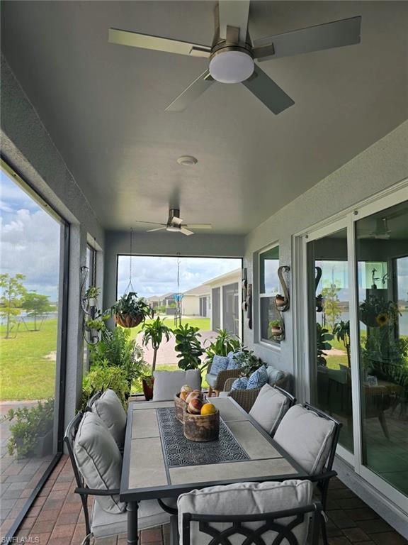 Screened outdoor living area with brick paver flooring, multiple ceiling fans, and large glass sliding doors