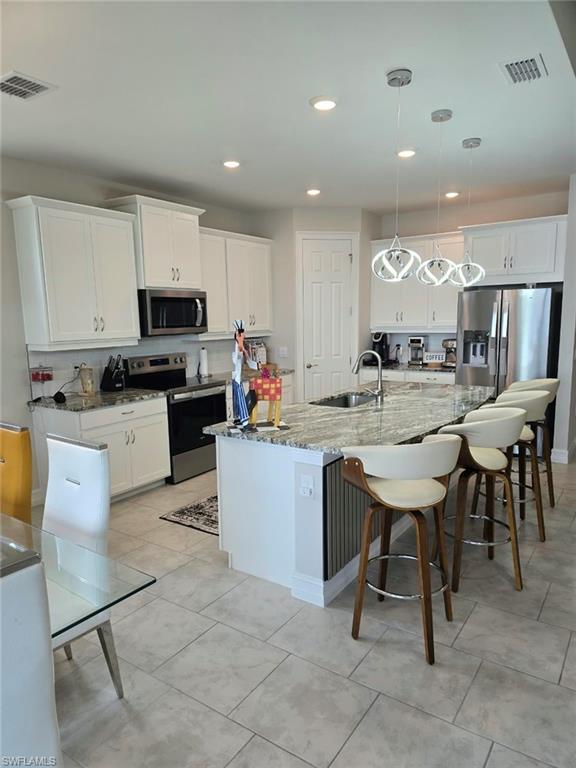 White cabinetry, stainless steel appliances, granite countertops, recessed lighting, and tile flooring