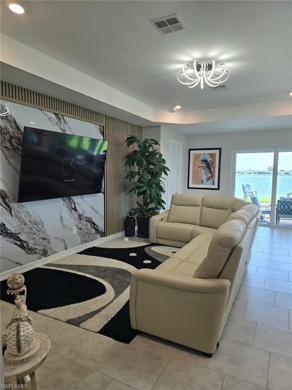 Recessed ceiling lighting, modern chandelier, large format tile flooring, accent wall with paneling and a marble-finish section, full-light glass door
