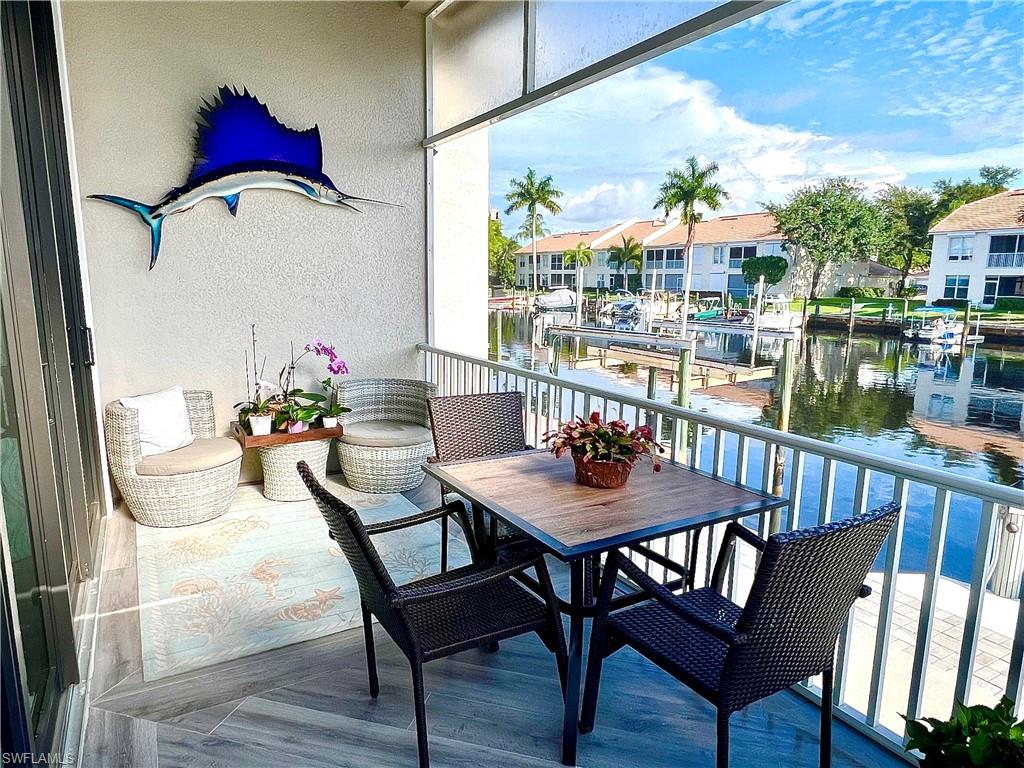 Waterfront balcony with tile flooring and a white railing overlooking a canal with multiple boats