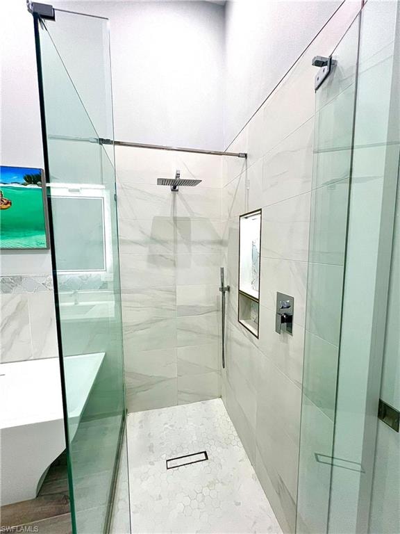 Frameless glass shower enclosure featuring a rainfall showerhead, handheld shower, and a built-in niche with accent trim