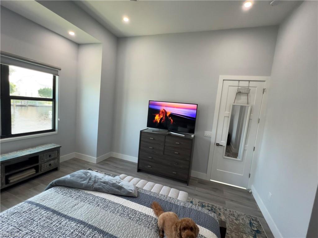 Spacious room featuring a large window with water frontage, high ceilings, recessed lighting, and wood-finish flooring
