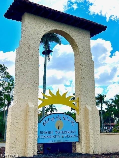 Archway entrance with a tiled roof, textured stucco columns, and a visible community sign