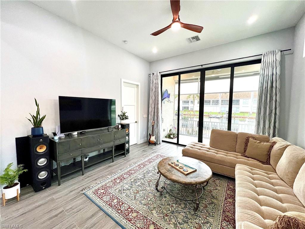 Spacious living area featuring large sliding glass doors, wood-finish tile flooring, a contemporary ceiling fan, recessed lighting, and white baseboards