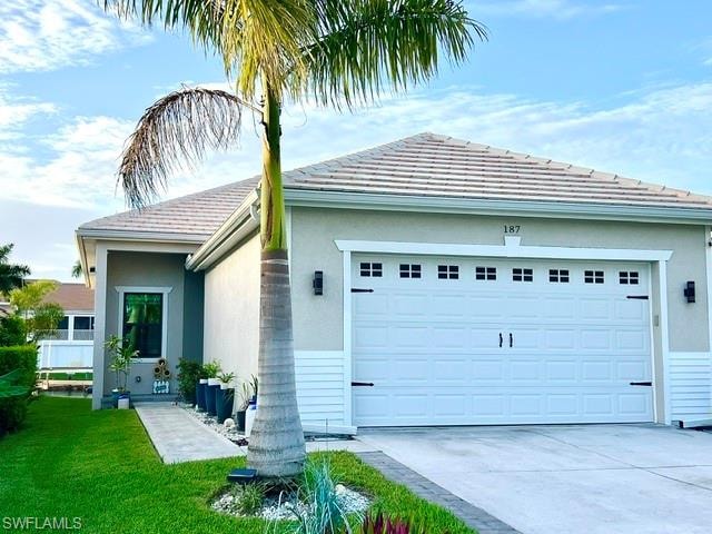 Stucco exterior with a tile roof, an integrated two-car garage, a concrete driveway, and a concrete walkway to the entry