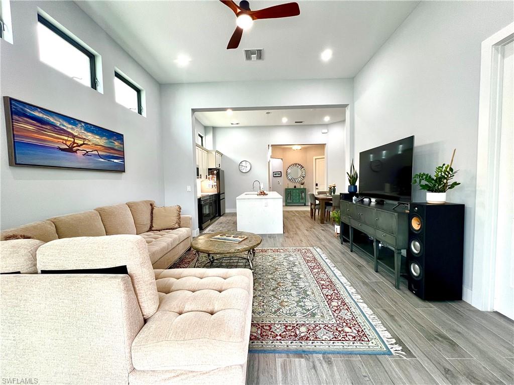 Spacious living area featuring high ceilings, wood-finish flooring, recessed lighting, a ceiling fan, and transom windows
