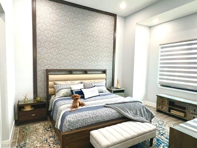 Accent wall with geometric pattern, recessed lighting, wood-finish flooring, and window with horizontal blinds