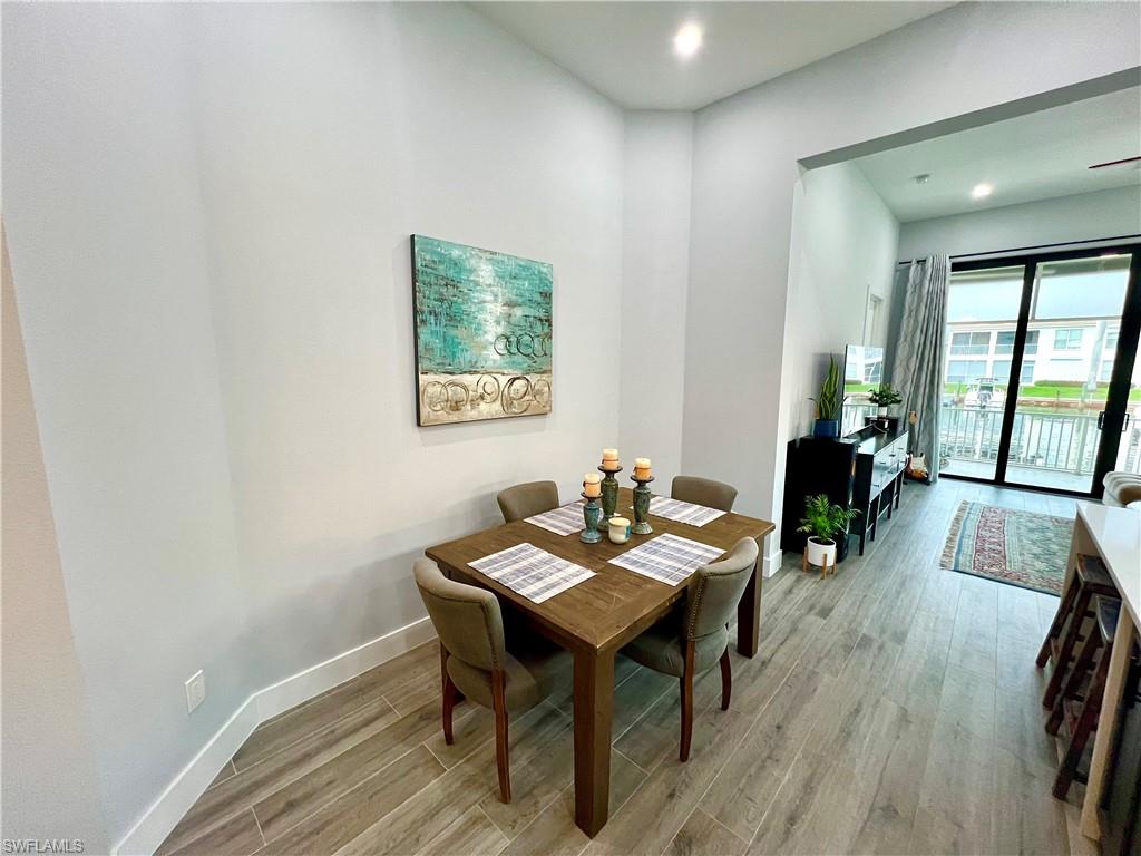Open-concept living area with wood-finish flooring, recessed lighting, and a sliding glass door leading to an outdoor space