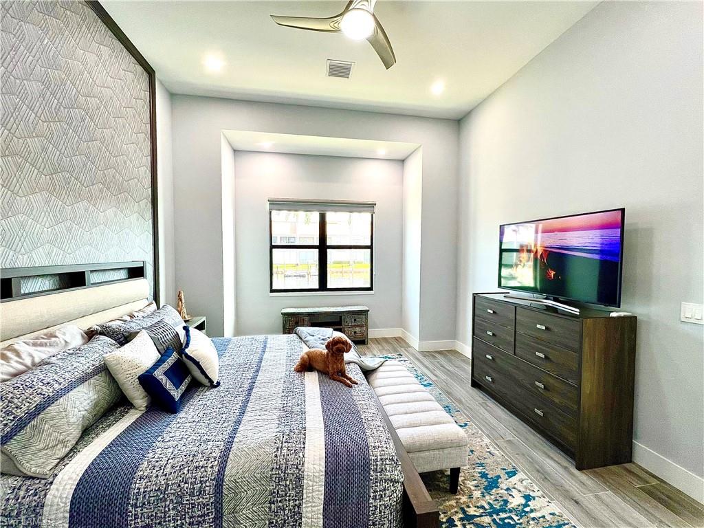 Spacious room featuring a textured accent wall with dark wood trim, recessed lighting, and a contemporary ceiling fan