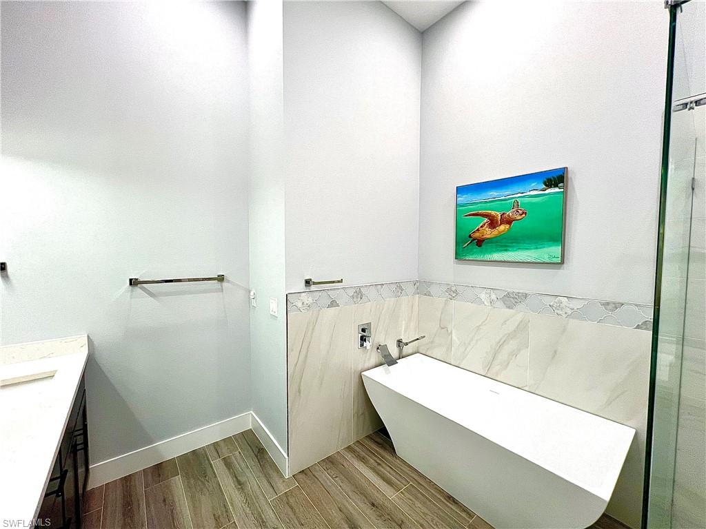 Freestanding soaking tub with wall-mounted faucet, complemented by large format tile and a decorative mosaic accent