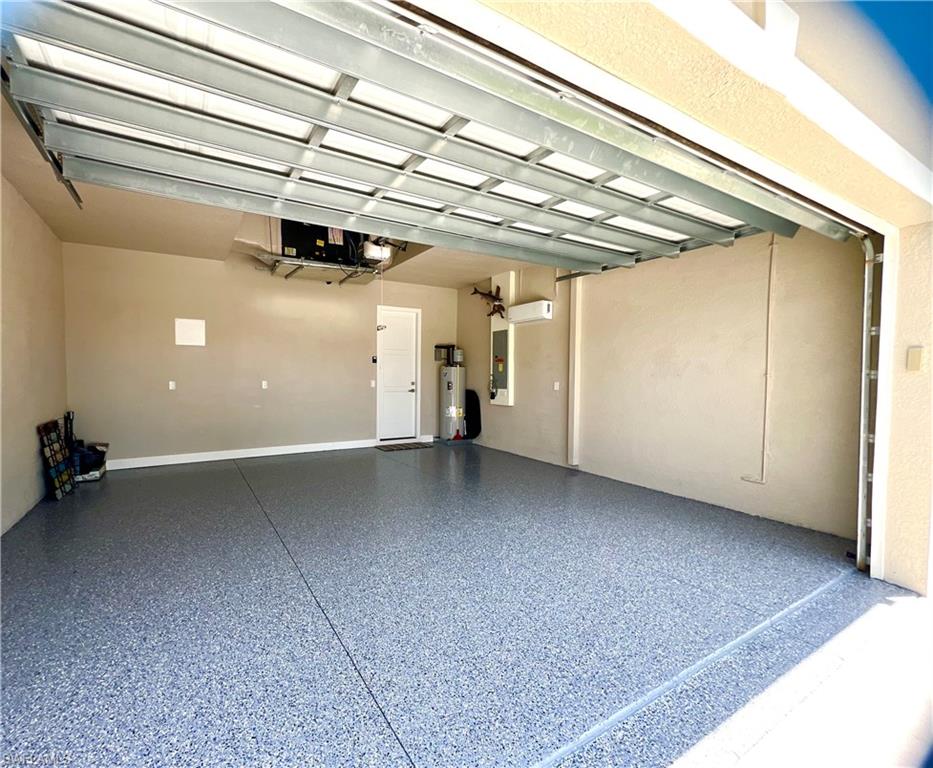 Spacious garage featuring an epoxy floor, automatic garage door, water heater, and an interior access door