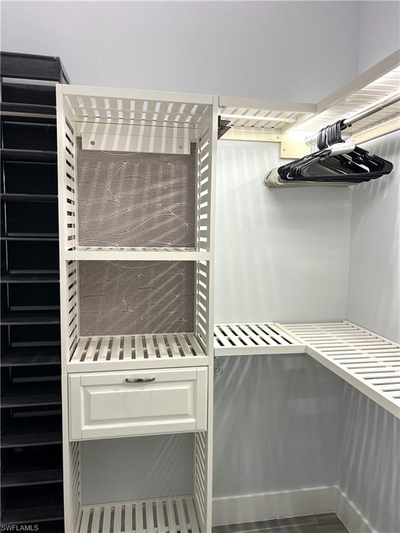 Custom closet organization system featuring slatted shelving, a built-in drawer with decorative paneling, and a hanging rod